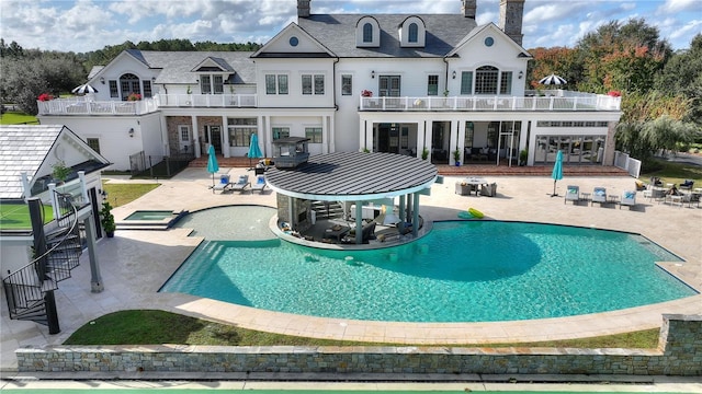 back of house featuring a swimming pool with hot tub and a patio
