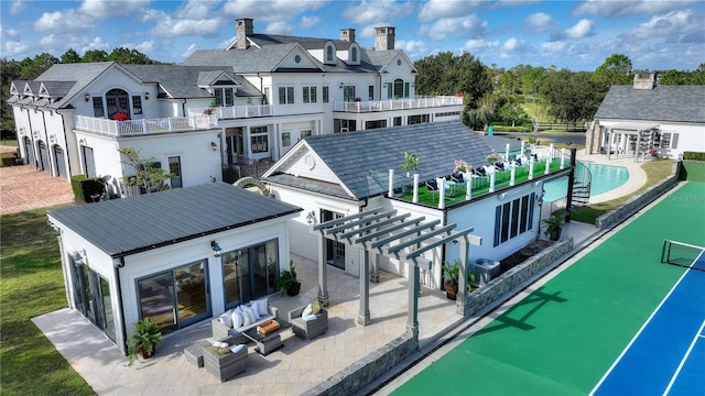 back of house featuring a patio area, a balcony, a pergola, and an outdoor living space