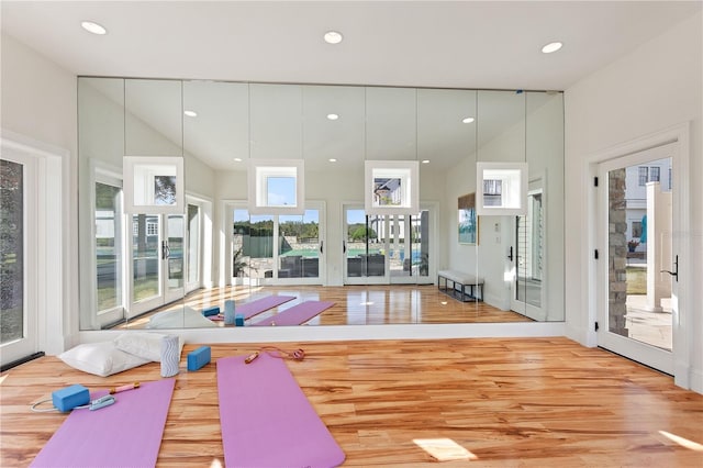 exercise area featuring lofted ceiling and light hardwood / wood-style flooring