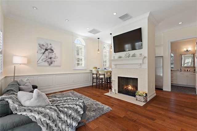 living room with a tile fireplace, crown molding, and dark hardwood / wood-style flooring