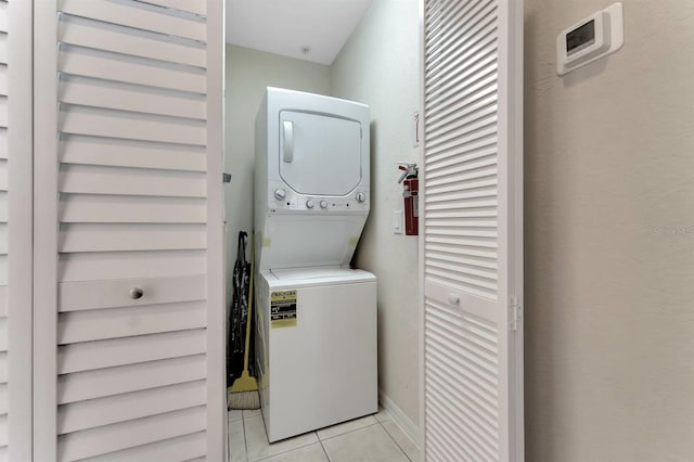 laundry area featuring light tile patterned flooring and stacked washer / drying machine