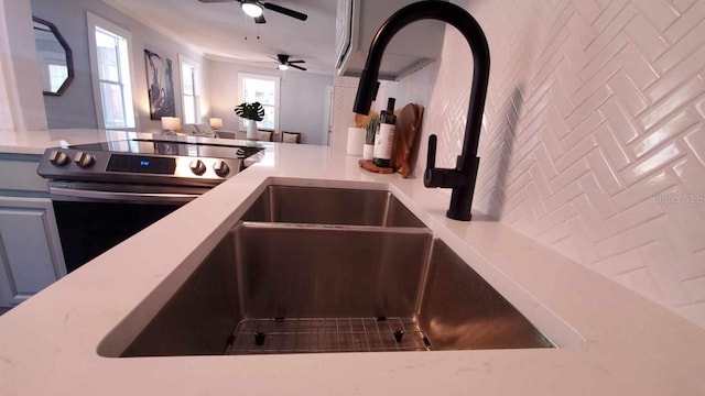 kitchen featuring stainless steel electric stove, ceiling fan, and sink