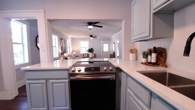 kitchen featuring stainless steel range with electric cooktop, kitchen peninsula, dark wood-type flooring, ceiling fan, and ornamental molding