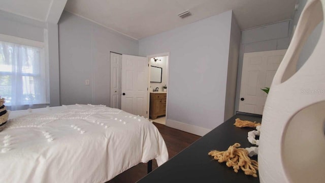 bedroom featuring dark hardwood / wood-style floors, connected bathroom, a closet, and sink