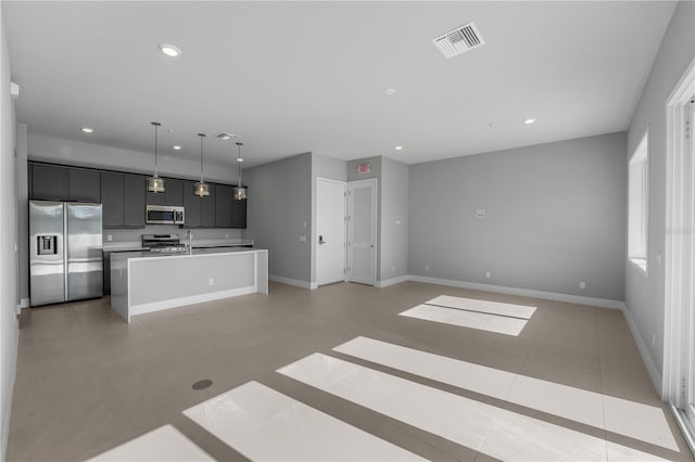 kitchen featuring sink, pendant lighting, appliances with stainless steel finishes, a center island with sink, and light tile patterned floors