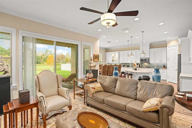 living room with light hardwood / wood-style floors, ceiling fan, crown molding, and sink