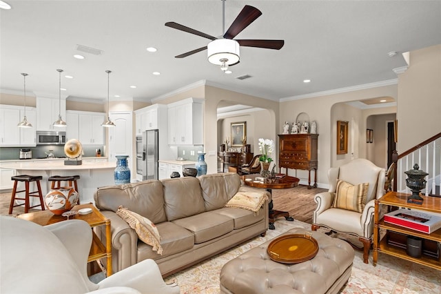 living room with ceiling fan, crown molding, and light wood-type flooring