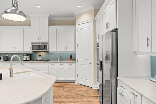 kitchen with backsplash, sink, light hardwood / wood-style floors, white cabinetry, and stainless steel appliances