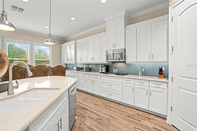 14372 Sunbridge Cir, Winter Garden, FL 34787 - kitchen featuring stainless steel appliances, crown molding, white cabinets, light countertops, and pendant lighting