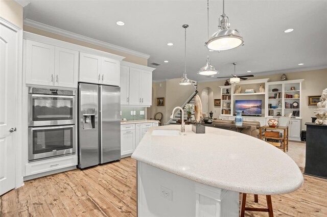 14372 Sunbridge Cir, Winter Garden, FL 34787 - kitchen with stainless steel appliances, light wood finished floors, ornamental molding, white cabinetry, and recessed lighting