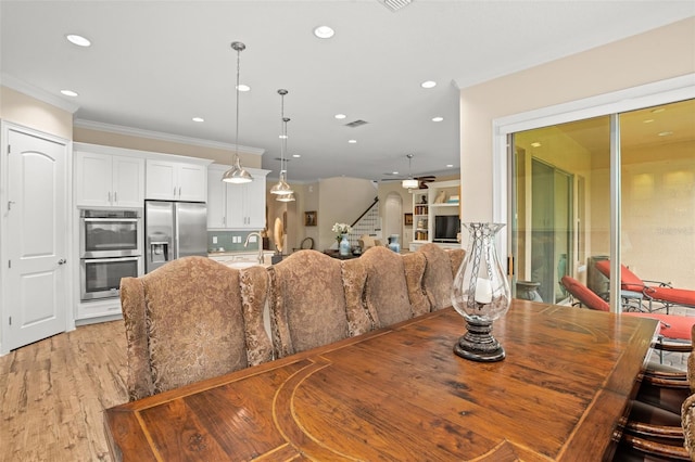 dining room with light wood-type flooring, ceiling fan, crown molding, and sink