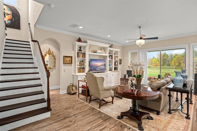 living room featuring a textured ceiling, ceiling fan, light hardwood / wood-style floors, and crown molding