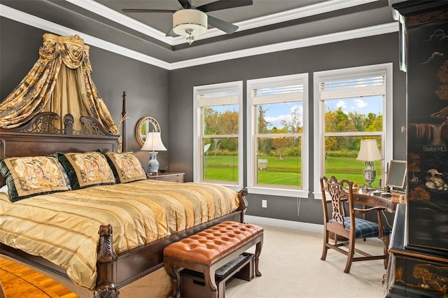 carpeted bedroom with ceiling fan, ornamental molding, and a tray ceiling