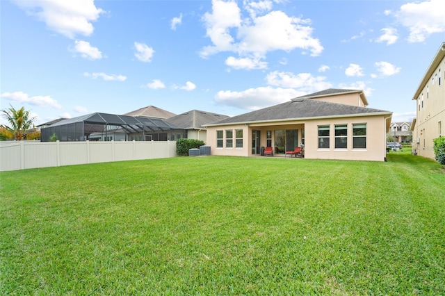 rear view of property with central AC and a lawn