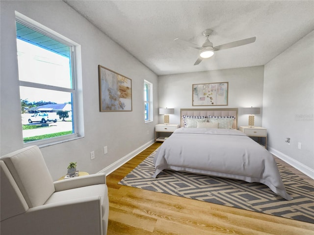 bedroom with a textured ceiling, hardwood / wood-style flooring, and ceiling fan