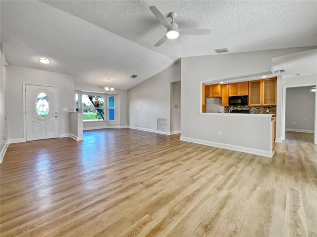 unfurnished living room featuring a textured ceiling, ceiling fan with notable chandelier, lofted ceiling, and light wood-type flooring