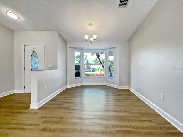 foyer entrance with a textured ceiling, hardwood / wood-style flooring, and a notable chandelier