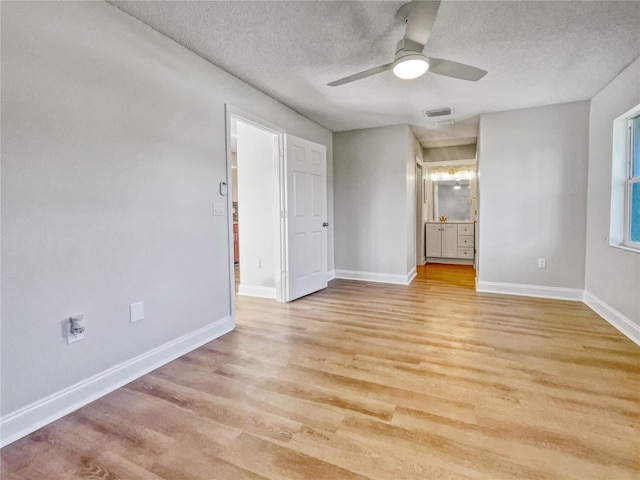 unfurnished bedroom featuring a textured ceiling, ensuite bathroom, light hardwood / wood-style flooring, and ceiling fan