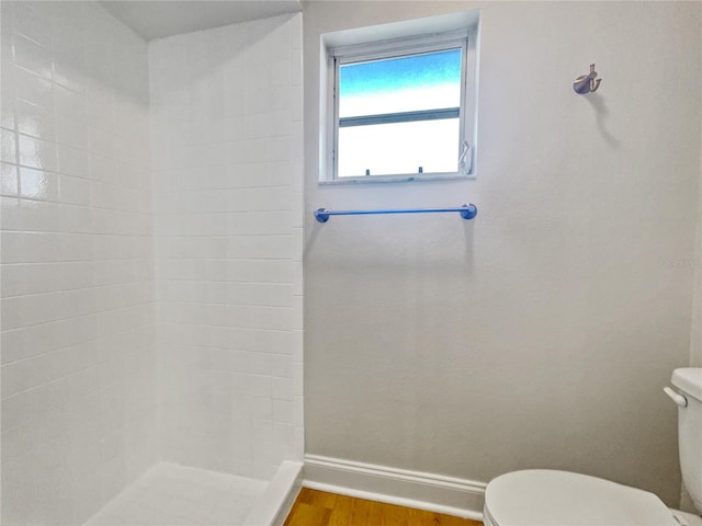 bathroom featuring a shower, hardwood / wood-style floors, and toilet