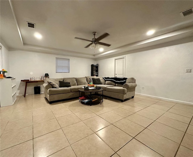 living room featuring light tile patterned floors, ceiling fan, and a tray ceiling