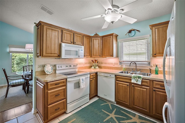 kitchen with sink, light tile patterned floors, white appliances, ceiling fan, and a textured ceiling