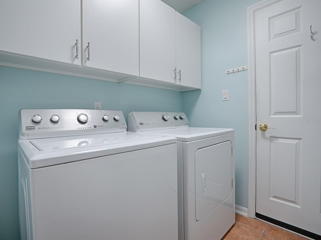 laundry area with cabinets, separate washer and dryer, and light tile patterned floors