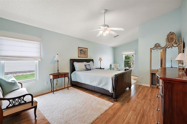 bedroom featuring multiple windows, ceiling fan, vaulted ceiling, and light hardwood / wood-style flooring