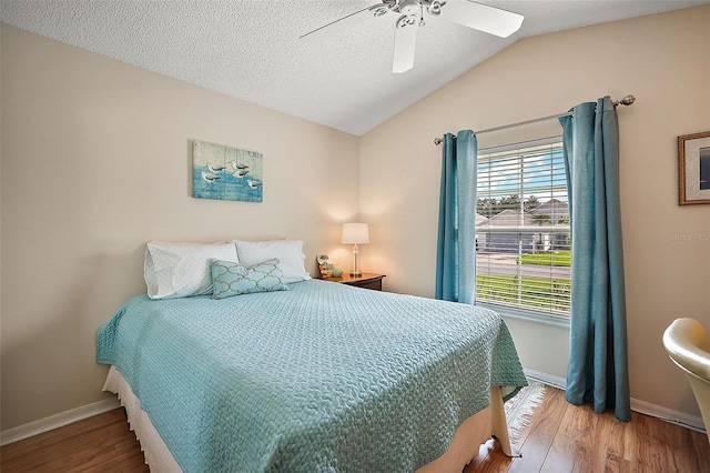 bedroom with wood-type flooring, lofted ceiling, a textured ceiling, and ceiling fan