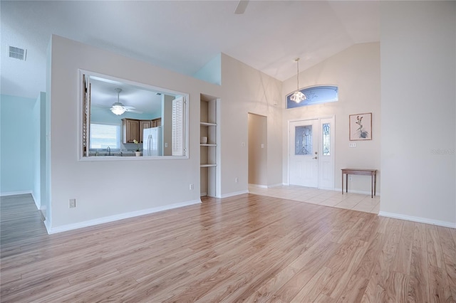 unfurnished living room featuring high vaulted ceiling, built in shelves, light hardwood / wood-style floors, and ceiling fan