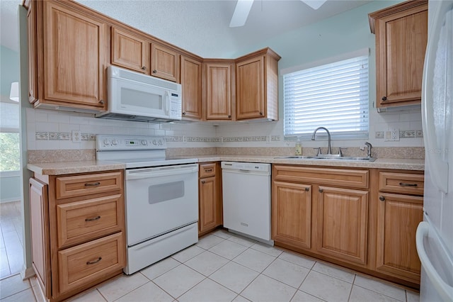 kitchen featuring light tile patterned flooring, white appliances, a healthy amount of sunlight, and sink