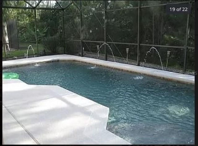 pool featuring glass enclosure and a patio