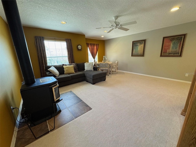 carpeted living room featuring a wood stove, baseboards, a ceiling fan, and recessed lighting