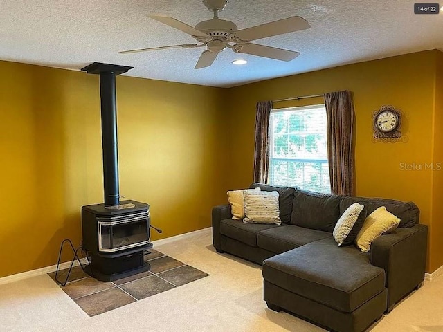 living area with a wood stove, carpet, baseboards, and a textured ceiling