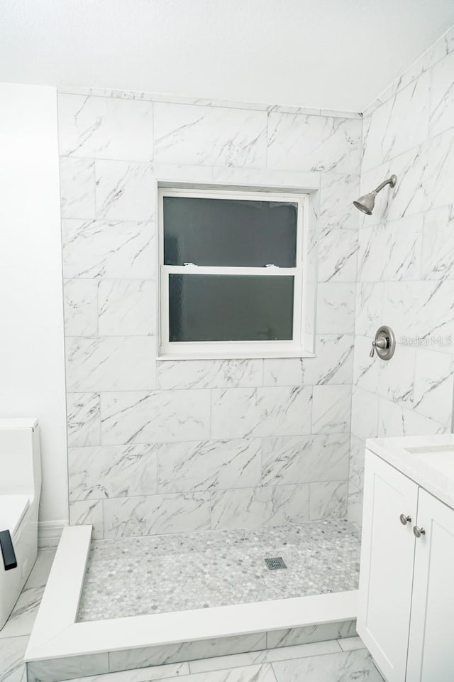 bathroom with tile patterned floors, vanity, a tile shower, and tile walls