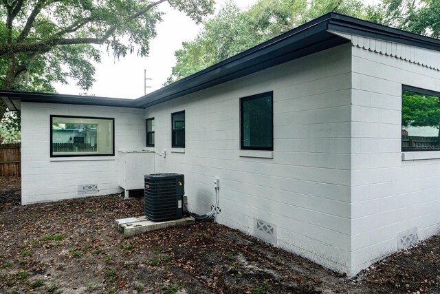 view of home's exterior with crawl space, cooling unit, and fence