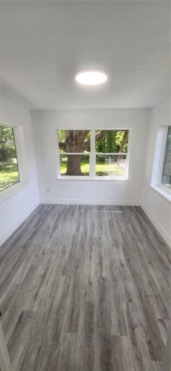 unfurnished room with baseboards and wood finished floors