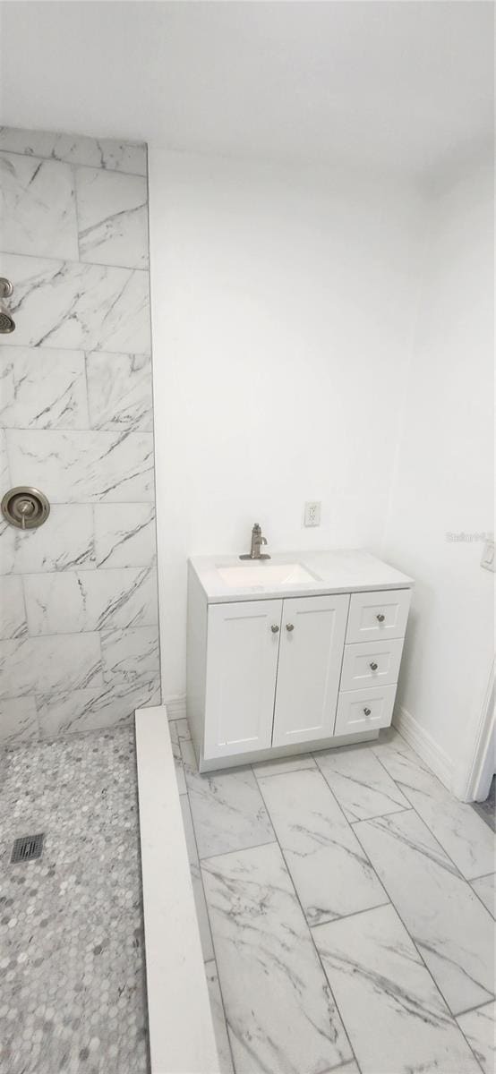 bathroom with tiled shower, vanity, and tile patterned flooring