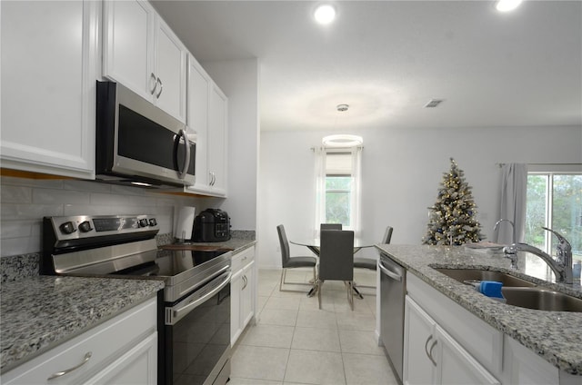 kitchen with white cabinetry, appliances with stainless steel finishes, sink, and light stone counters