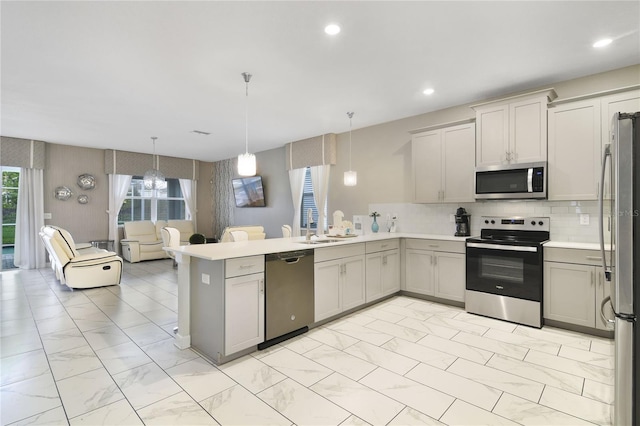 kitchen featuring hanging light fixtures, tasteful backsplash, kitchen peninsula, stainless steel appliances, and sink