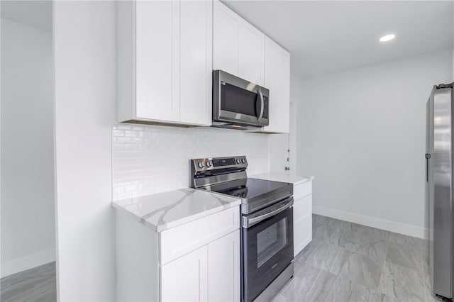 kitchen featuring white cabinetry, appliances with stainless steel finishes, light stone counters, tasteful backsplash, and light tile flooring