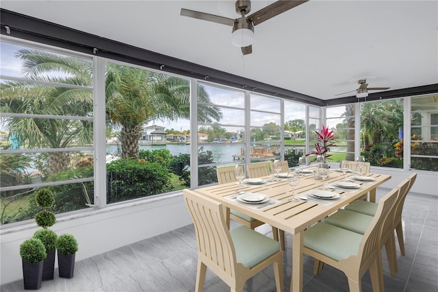 sunroom with ceiling fan and a water view