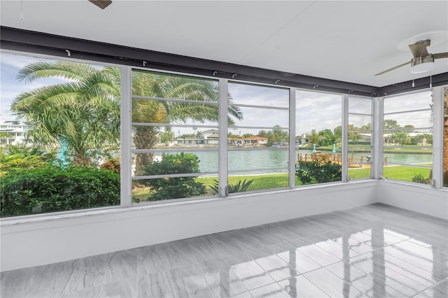 unfurnished sunroom with ceiling fan and a water view