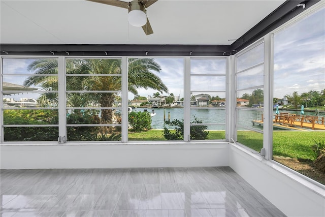 unfurnished sunroom with a wealth of natural light, a water view, and ceiling fan