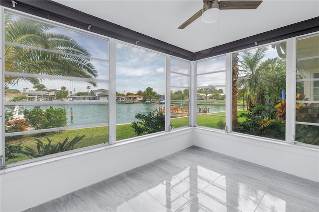 unfurnished sunroom with a water view and ceiling fan