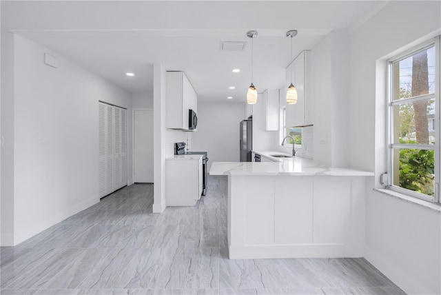 kitchen featuring kitchen peninsula, decorative light fixtures, light tile floors, and appliances with stainless steel finishes