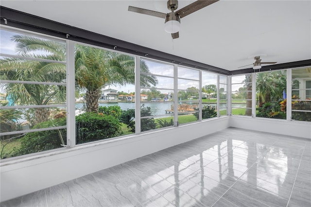 unfurnished sunroom featuring a healthy amount of sunlight, a water view, and ceiling fan