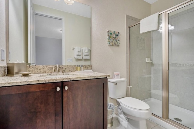 bathroom with tile patterned floors, a shower with shower door, toilet, and vanity