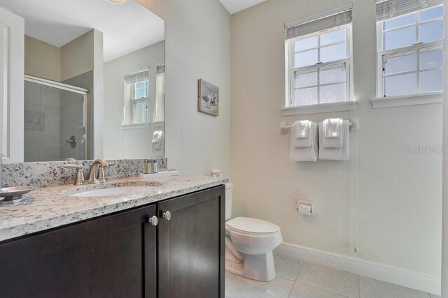 bathroom with vanity, tile patterned floors, a shower with door, and toilet