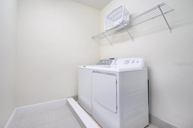 clothes washing area with light tile patterned flooring and washer and clothes dryer