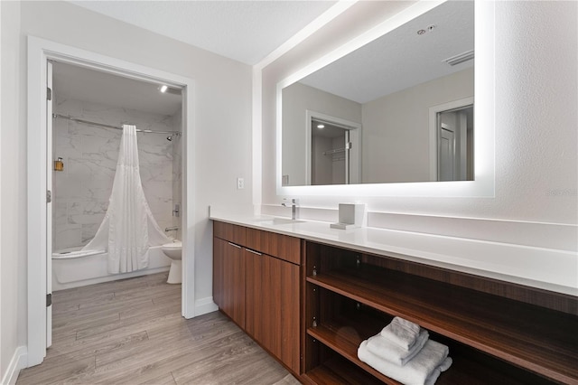 full bathroom featuring vanity, hardwood / wood-style flooring, toilet, a textured ceiling, and shower / tub combo